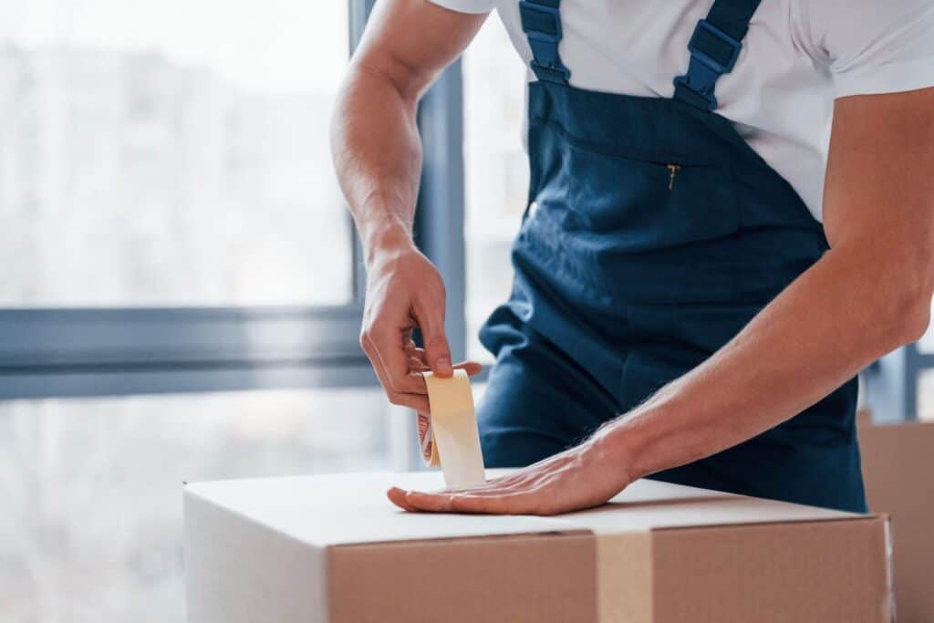 A male mover employee packaging a box