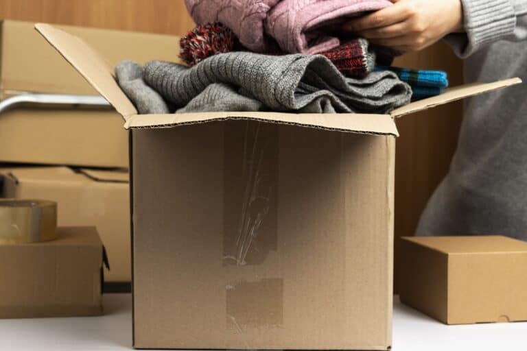 a woman is packing clothes in a box