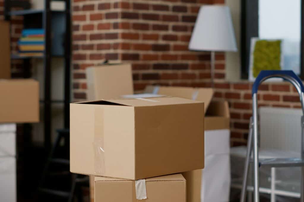 A stack of cardboard boxes in a house with brick walls