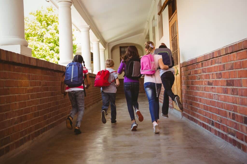 The kids are running in the school corridor.